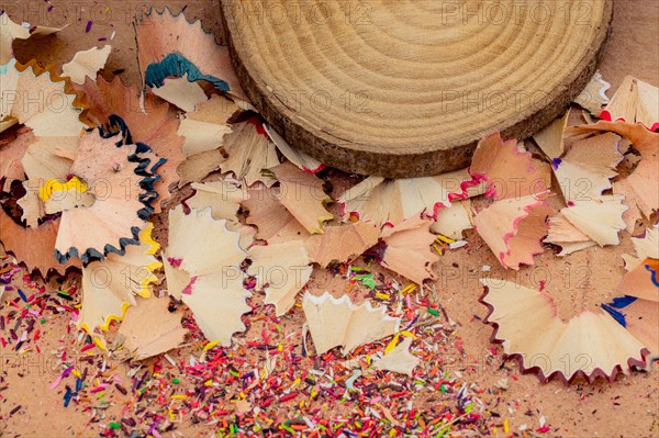 Colorful pencil shavings and a piece of wood