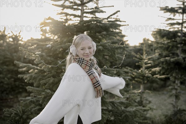 Teenage girl in front of fir trees