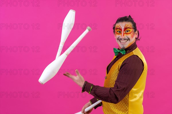 Clown with white facial makeup on a pink background