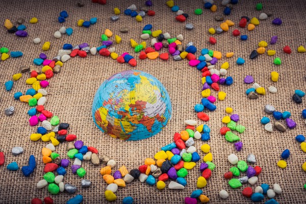 Globe in the heart form shaped by colorful pebbles