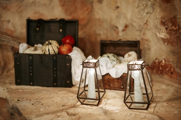 Old lanterns with lightened candles and wooden cases with pumpkins in the background