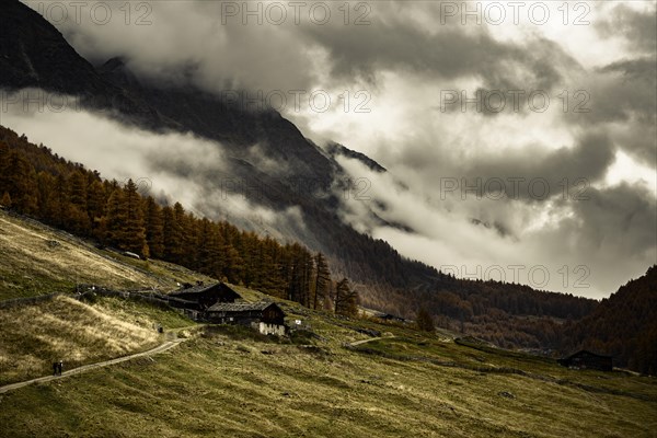 Alpine hut in autumnal mountain landscape with threatening cloudy sky