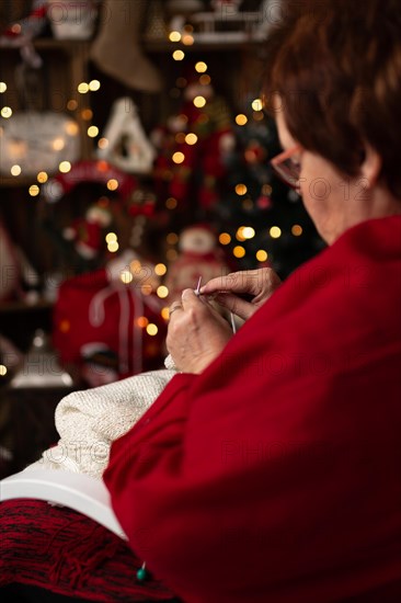 Grandmother sews a plush owl in Christmas arrangement. In studio