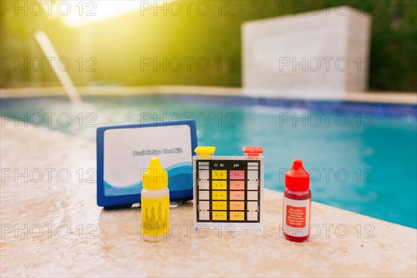 Chlorine test kit on the edge of the pool. PH tester for pool maintenance. Water test kit for swimming pools