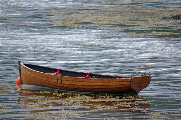 Small wooden rowing boat lying in the shallow waters of Plockton Harbour