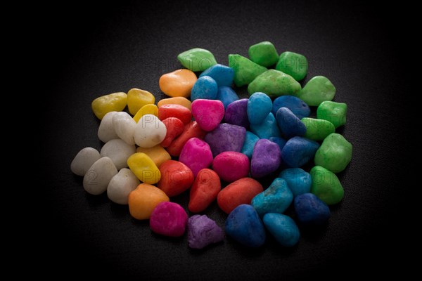 Pile of little colorful pebbles on black background