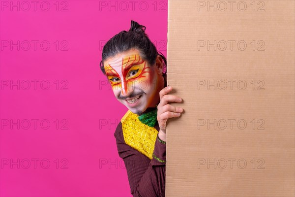 Clown with white facial makeup showing a sign on a pink background
