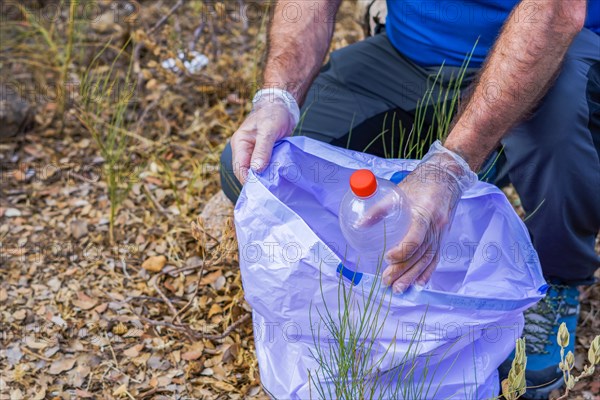 Environmentalist man with garbage bags picking up garbage from the field and taking care of the environment