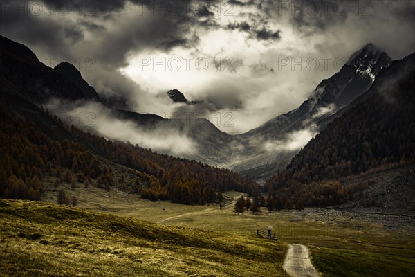 Way cross with path in autumnal mountain landscape with threatening cloudy sky