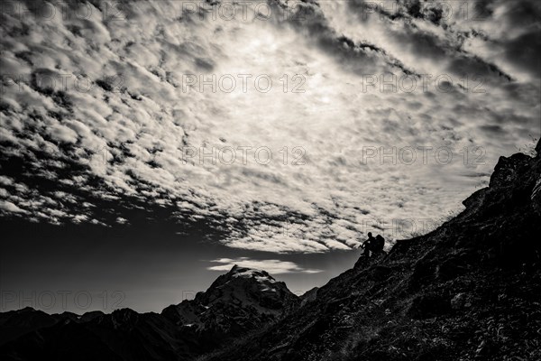 Mountaineer in backlight with cloudy sky in front of Ortler summit massif