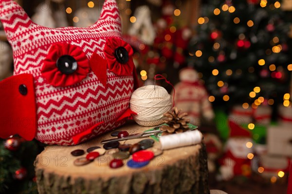 Grandmother sews a plush owl in Christmas arrangement. In studio