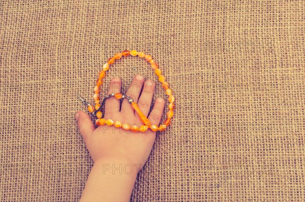 Set of praying beads of various colors in hand on canvas