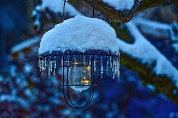 Solar garden light covered with snow at dusk