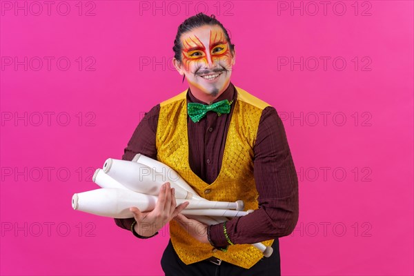 Juggler in a vest and with painted face juggling clubs on a pink background