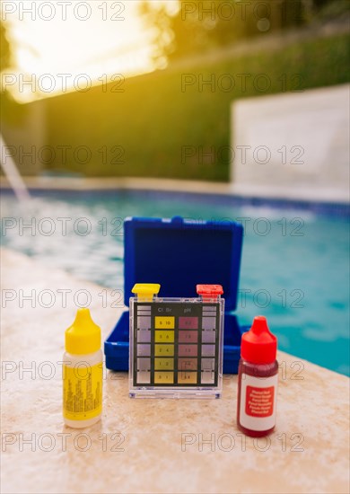 Chlorine test kit on the edge of the swimming pool Mini tester for pool maintenance. Water test kit for swimming pools