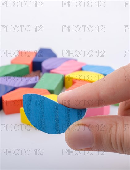 Colorful wooden pieces of a logic puzzle in hand