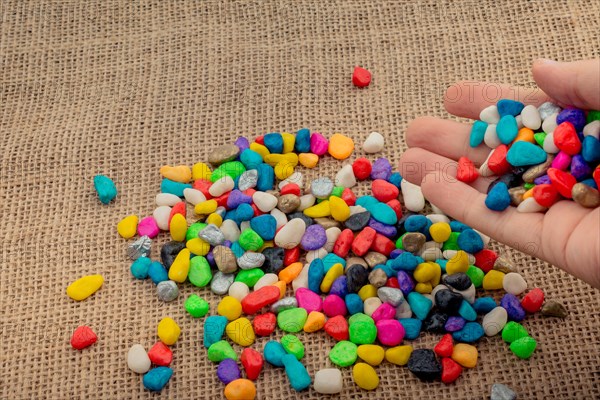 Colorful little pebbles in hand and on canvas ground