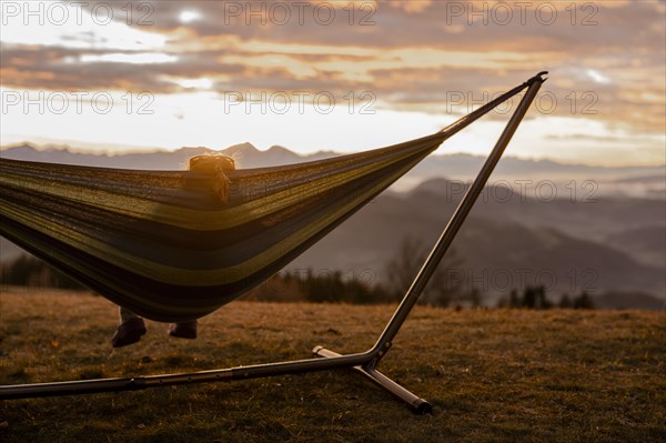 Woman in a hammock at sunset in the mountains