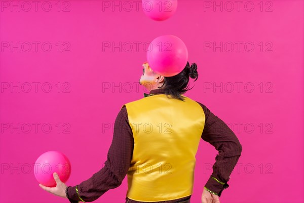 Clown with white facial makeup on a pink background