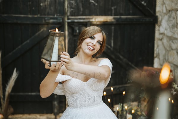 Portrait of beautiful bride holding lantern in rustic background