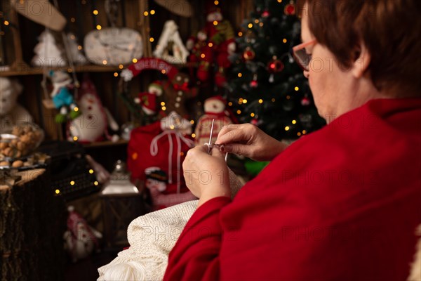 Grandmother sews a plush owl in Christmas arrangement. In studio