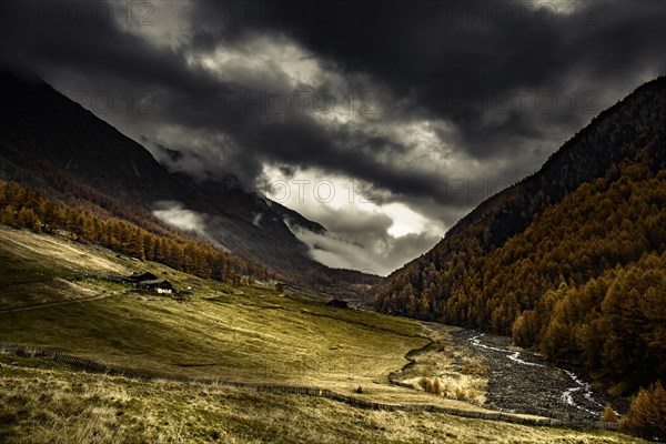 Alpine hut in autumnal mountain landscape with threatening cloudy sky