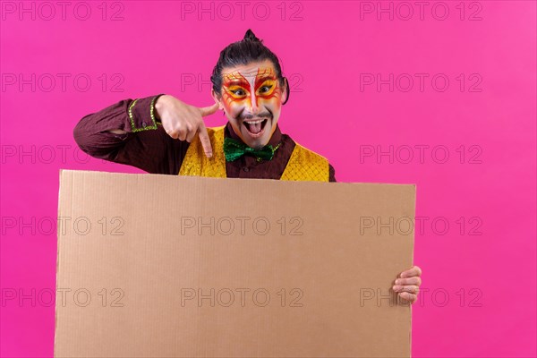 Clown with white facial makeup showing a sign on a pink background