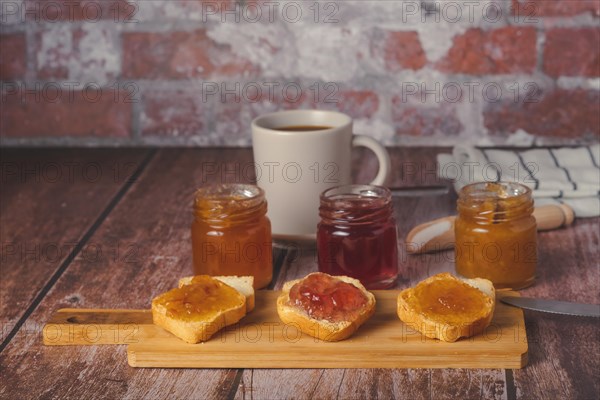 Small pieces of toast with jam and coffee on a wooden table