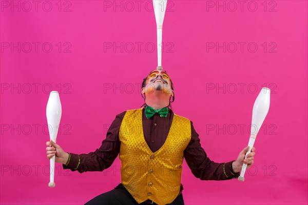 Clown with white facial makeup on a pink background