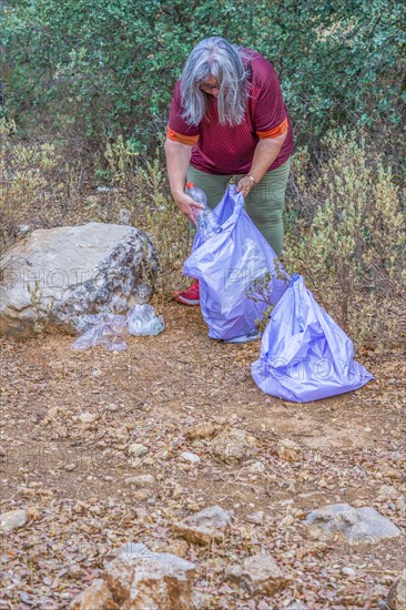 Woman ecologist with garbage bags picking up garbage from the field and taking care of the environment