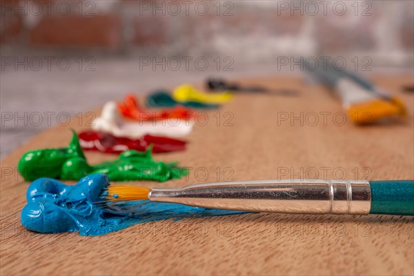 Close-up brush with out-of-focus oil paint colors on a wooden palette