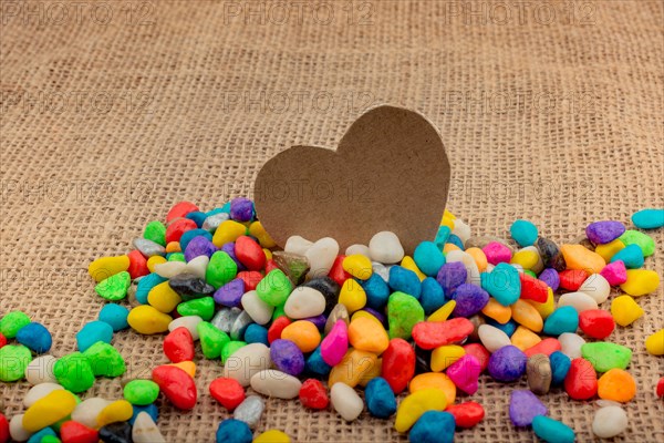 Paper heart amid colorful pebbles on canvas ground