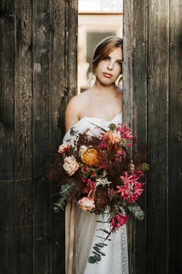 Beautiful bride with a bouquet with wooden door background as a background