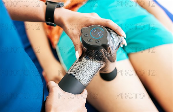 Physiotherapist using massage gun to relieve muscle pain