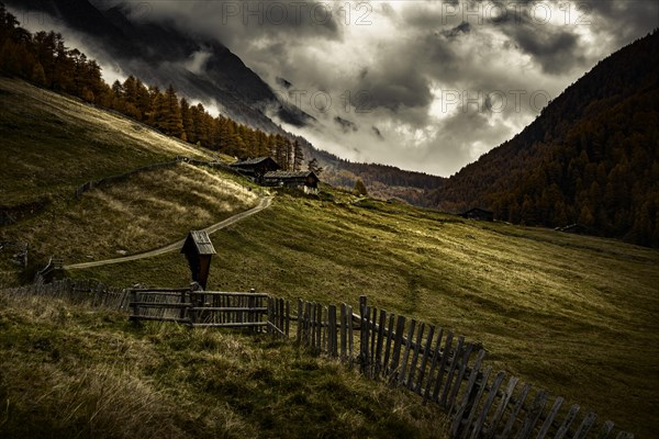 Alpine hut in autumnal mountain landscape with threatening cloudy sky