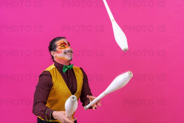 Clown with white facial makeup on a pink background