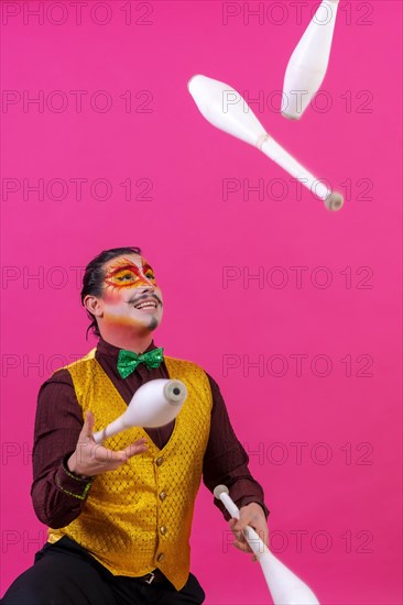 Clown with white facial makeup on a pink background