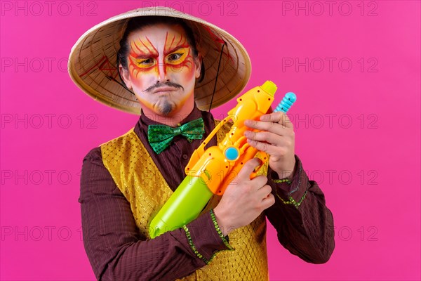 Clown with white facial makeup on a pink background