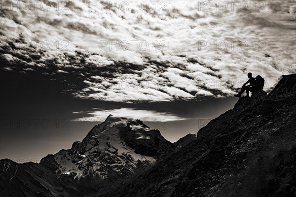 Mountaineer in backlight with cloudy sky in front of Ortler summit massif