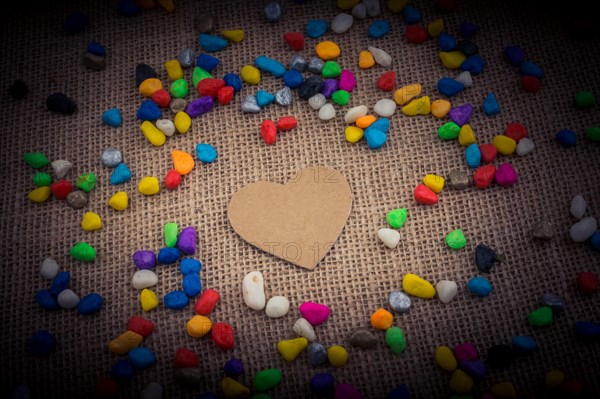 Paper heart amid colorful pebbles on canvas ground