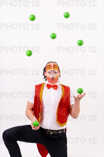 Smiling juggler juggling green balls isolated on white background