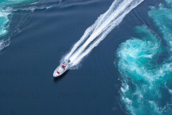 Powerboat between huge whirlpools and eddies in the water of a fjord