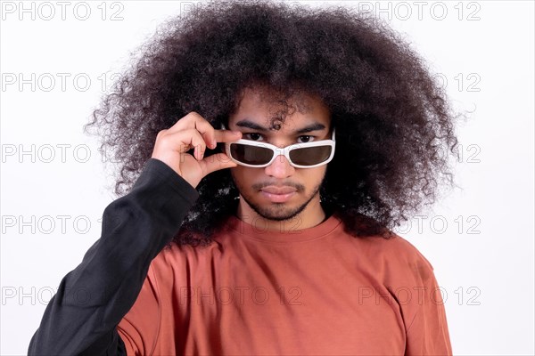 Portrait wearing sunglasses and looking at the camera. Young man with afro hair on white background