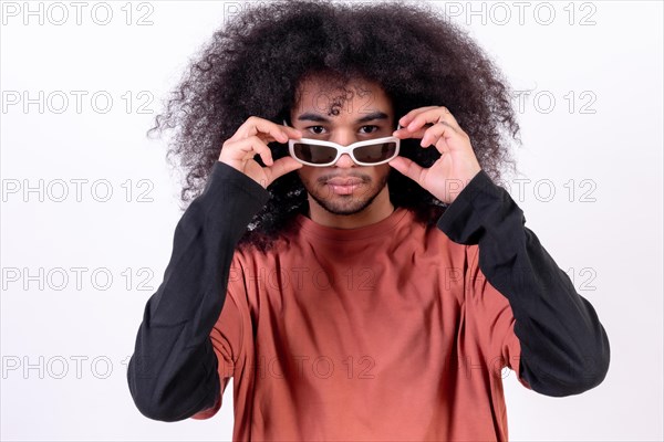 Portrait wearing sunglasses and looking at the camera. Young man with afro hair on white background