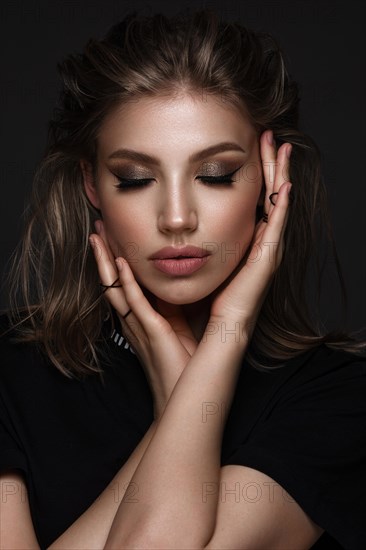 Portrait of a beautiful woman in a black dress with creative makeup in a fashion style. Beauty face. The photo was taken in a studio on a black background