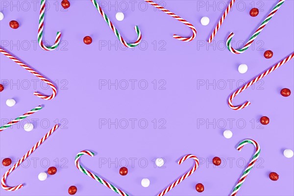 Christmas Candy canes forming frame around purple background with copy space