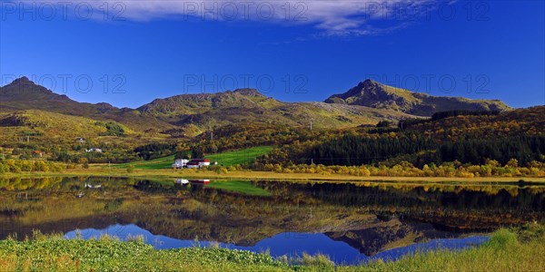 Autumn coloured forests and mountains reflected in a lake