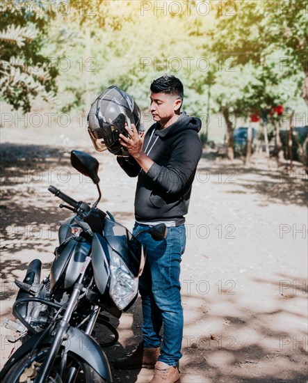 Young motorcyclist man putting on safety helmet