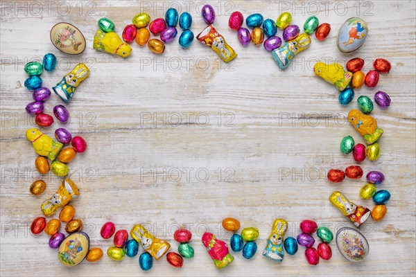 Frame of colourful Easter sweets on wood