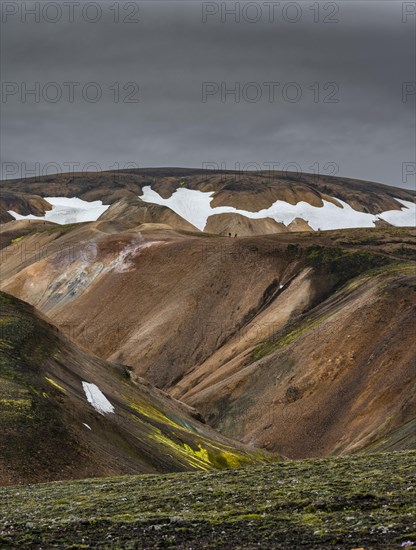 Hikers on colourful rhyolite mountains with remnants of snow